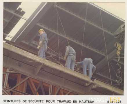 Ouvriers portant des ceintures de sécurité pour des travaux en hauteur sur un bâtiment de l'usine de Pont-à-Mousson (Meurthe et Moselle) le 6 novembre 1975.