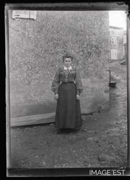 Femme debout devant une maison (Amance)